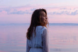 Woman standing in the ocean at sunset
