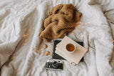 book camera and tea on bed