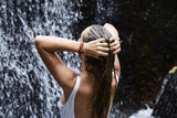 Woman washing hair under a waterfall