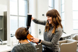 Hair dresser blow drying client's hair